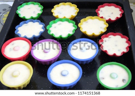 dough for cupcakes in multi-colored silicone molds on a baking tray. delicious pastry cooked at home, dessert for tea.