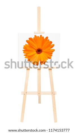 Creative conceptual idea easel with calendula flower isolated on white background