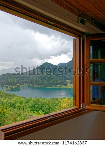 wooden window frame with view to a mountain lake, fall weather