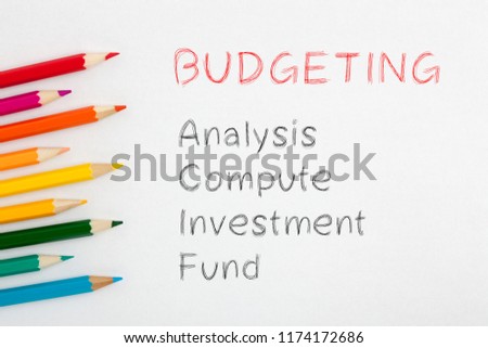 Budgeting written on white background by colour pencils. Business concept.