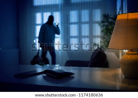 Burglar or intruder inside of a house or office with flashlight Royalty-Free Stock Photo #1174180636