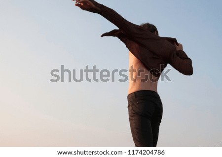 Man putting on shirt blue sky