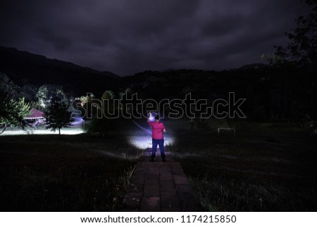 Silhouette of man in the forest on the night. Silhouette of person standing in the dark forest with light. Dark night in forest. Surreal night forest scene. Horror Halloween concept.