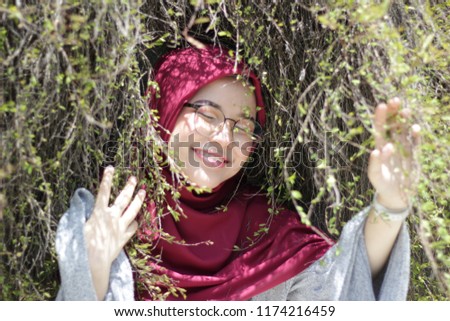 Close up portrait of a beautiful young Asian girl wearing hijab with background of plant roots. 