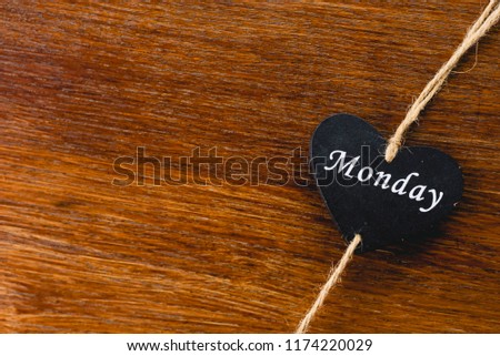 Heart of black wood with day of the week written on it, Monday.