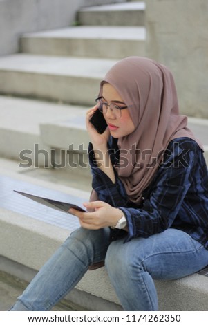 business women wearing hijab handling phone and note board discussing a project. Business concept.