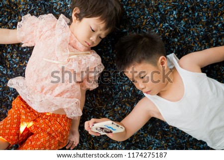 two chinese children addicted tablet, asian child watching tablet, kid use telephone together on their bed, play phone, kid addict smartphone
