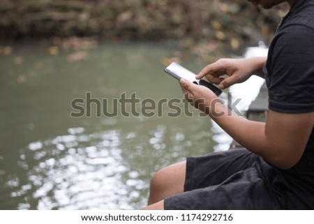 People wearing gray shirts sitting on wooden bridges crossing streams are discussing the way with application on mobile.