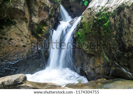 calm nature stream waterfall around the rocks in forest