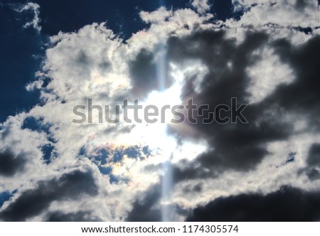 A stunning photograph of the sun's rays shining through fluffy clouds in Brisbane, Australia. 