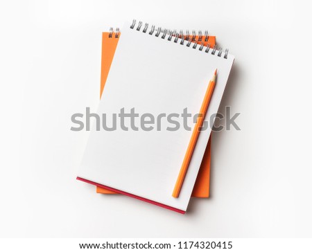 Design concept - Top view of orange and red spiral notebook and color pencil collection isolated on white background for mockup