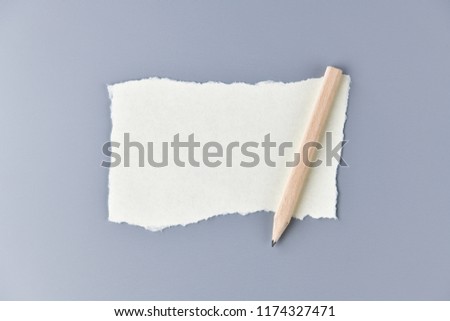 White paper message note with pencil on gray background.
