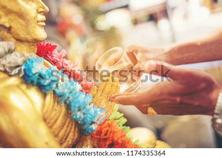 Water blessing ceremony for Songkran Festival or Thai New Year. People paying respects to a statue of Buddha by pouring water onto it.