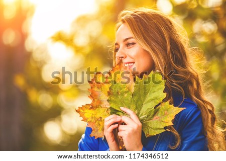 Cute smiley woman holding autumn leafs in the nature. Royalty-Free Stock Photo #1174346512