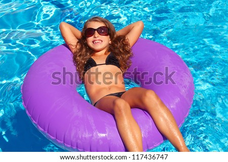 bikini children girl with sunglasses relaxed on purple inflatable pool ring