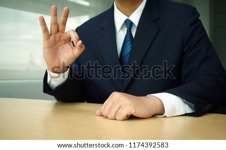 Businessman doing an okay symbol on table