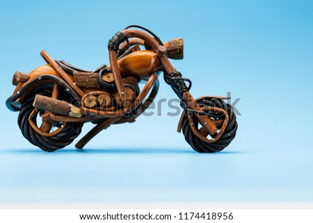Motorcycle toy in brown and black colour texture isolated on blue background, with wooden handmade.