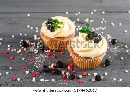 Creamy cupcakes with blueberries on the wooden background
