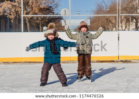 two funny little boy on the ice rink in winter