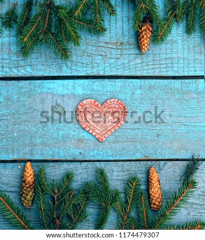 a New year and Christmas card / a wooden heart and spruce branch on the blue wooden surface
