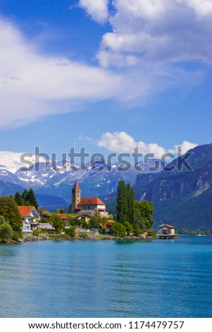 Panoramic view to the Brienz town on lake Brienz by Interlaken, Switzerland. Old fishing town with beautiful church and snow covered Alps mountains on background. Switzerland, Europe. Royalty-Free Stock Photo #1174479757