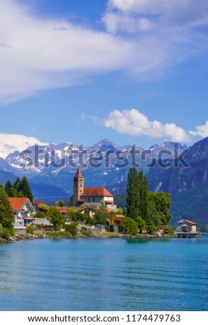 Panoramic view to the Brienz town on lake Brienz by Interlaken, Switzerland. Old fishing town with beautiful church and snow covered Alps mountains on background. Switzerland, Europe. Royalty-Free Stock Photo #1174479763