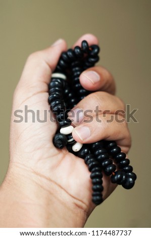 male hands praying holding a rosary