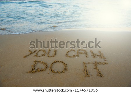 You can do it. Motivational inspirational message concept written on the sand of beach