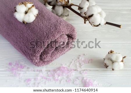 Violet towel and branch of cottton on the white wooden background