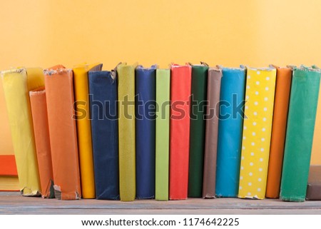 Book stacking. Open hardback books on wooden table and yellow background. Back to school. Copy space for ad text.