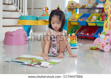 Asian Girl playing with her picture book at home