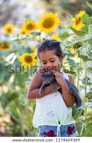Little girl playing with her kitty in sunflower field