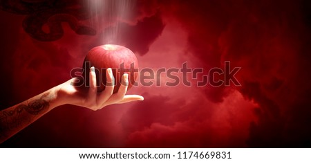 Woman hand with red apple isolated on red sky background, Christianity sin. Royalty-Free Stock Photo #1174669831