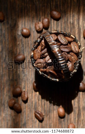 Coffee beans in a beautiful wicker basket on a wooden table background
