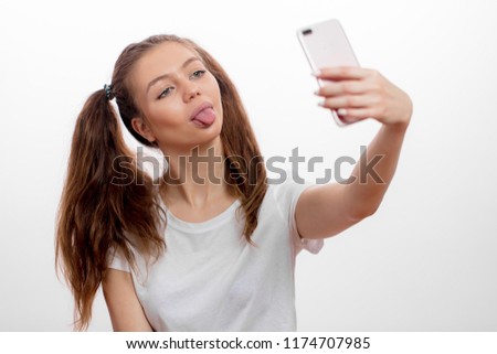 funny, awesome girl sshowing her tongue while taking selfie. craziness, mad woman sticking her tongue out while holding smart phone. free time,