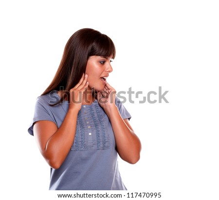 Surprised young woman looking to her left on blue shirt at isolated background - copyspace