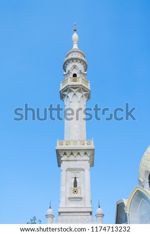 White tower on blue sky background. The white tower with a balcony.