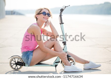 Young girl rests and sits on kick scooter at summer. concept of healthy lifestyle
