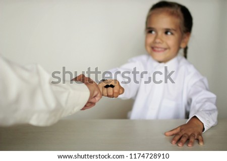 A cute little girl and her grandmother showing their fists with felt moustaches rings, happy father day and men health concept