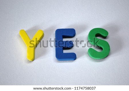 Word YES from colorful 3D foam letters on white background