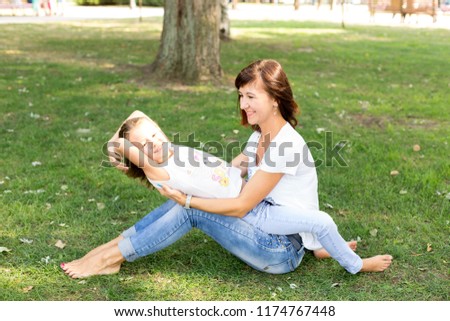 daughter and mother on the lawn.in a white t-shirt and jeans. a walk in the Park. child. mother daughter. summer.