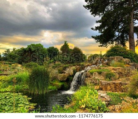 Beautiful rock garden with waterfall under a dramatic grey sky at sunset