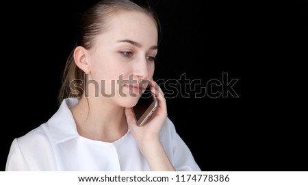 Front view of a young intellectual doctor on a black background with text space. The medical worker talking on a cell phone