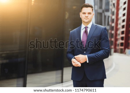 man in business suit is standing by office at sunrise.