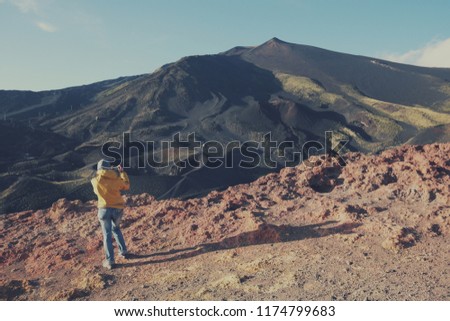 back view female tourist taking picture of summit Etna Volcano with mobile phone, Sicily