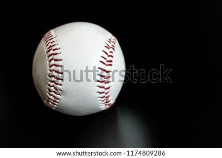 white baseball with red seams leather ball on black background.