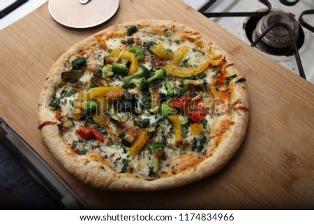 A pizza on a cutting board sitting on a stove shot from above