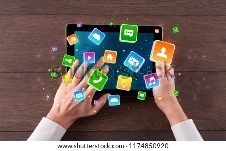 Hand using tablet with colourfull bounce application symbols and icons concept