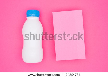 White plastic bottle with blue lid with paper sticker for text on a pink background