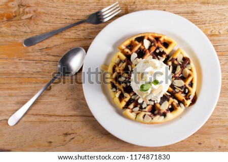 Dessert,Homemade waffles with vanila ice cream, chocolate topping and whipping cream on wooden background
